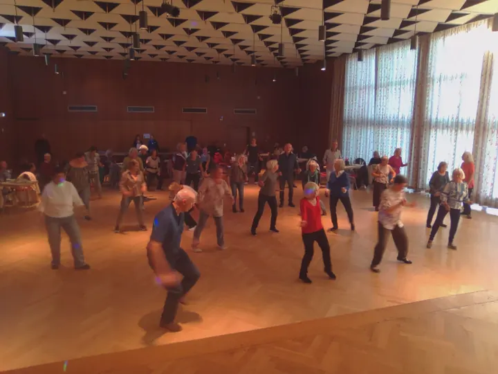 Menschen tanzen gemeinsam im Saal des Bürgerhauses Cappel in Marburg.
